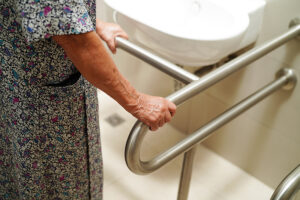 An elderly woman has bars installed in her bathroom for additional bathroom safety.