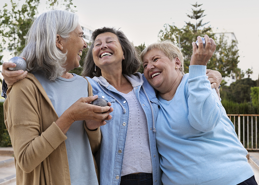 Senior women embracing each other while enjoying the health benefits of laughter.