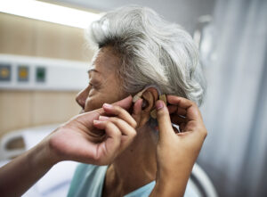 An elderly woman gets hearing aids to help improve her hearing.