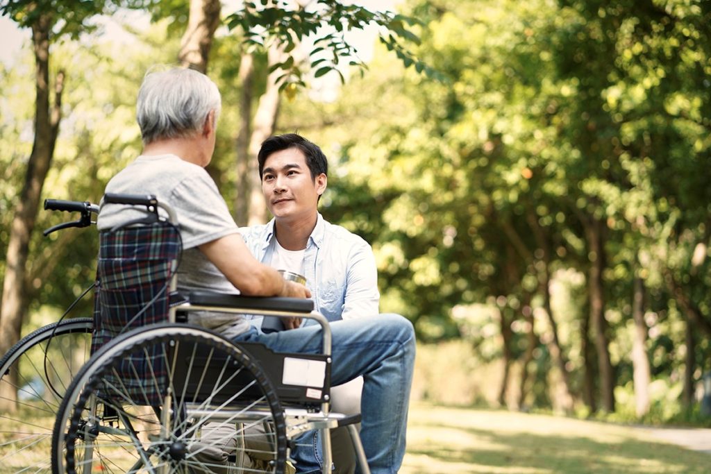 Man talks to older man in wheelchair