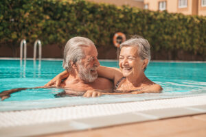 Two older adults enjoy swimming and wonder how very hot weather affects the elderly.