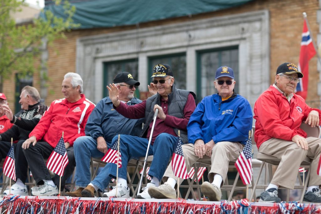 senior Veterans look out to crowd during a veterans day parade