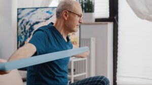 At-Home Workouts That Are Perfect for Older Adults. Senior man uses workout band.
