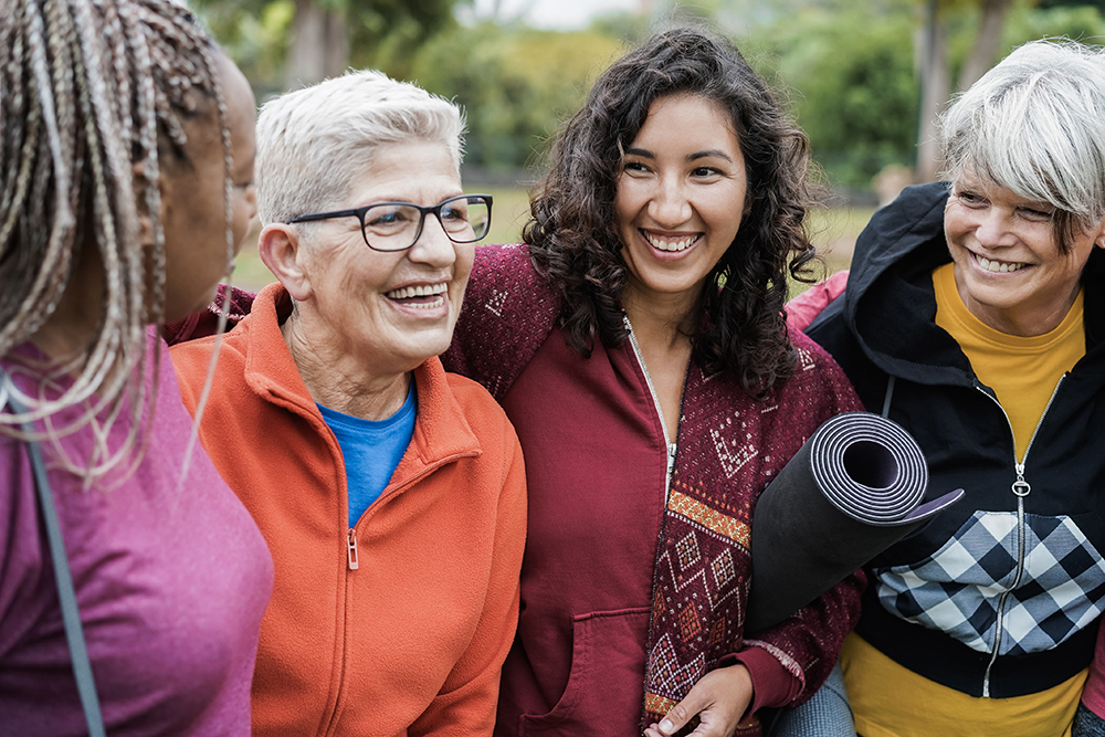 A group of women in an active adult living community smile as they leave an exercise class.