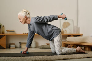 an elderly woman does a strength exercise for seniors at home.