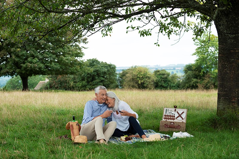 Spring Activities for Seniors. Man and woman enjoy picnic outdoors. 