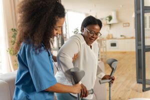 Skilled Nursing vs Long Term Care. Woman helps older woman with crutches.