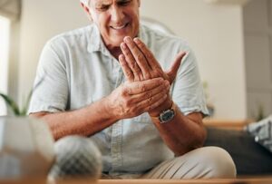 Arthritis and Older Adults. Older man holds hand in pain.