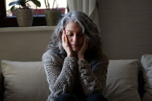 Woman sits with face in hands looking worried