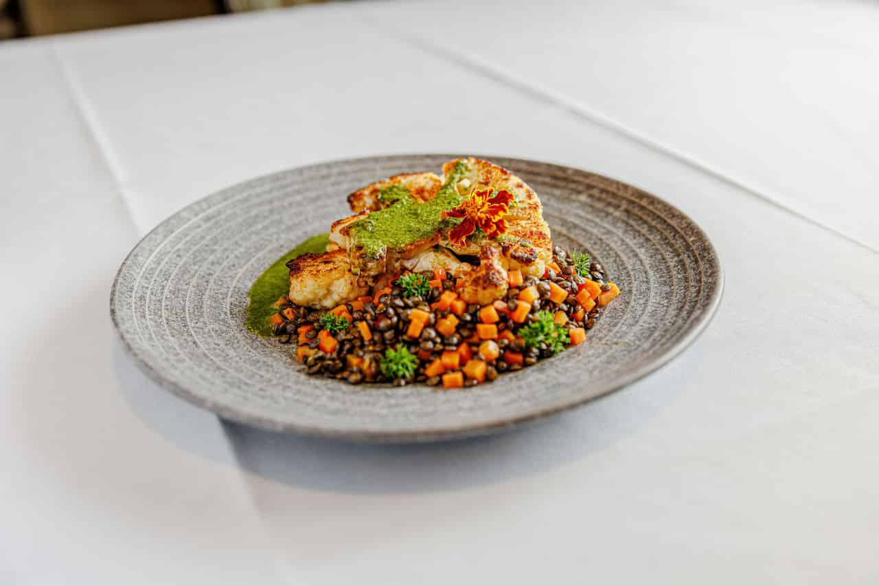 a photo of an elegant dining dish from Alma Via de San Francisco's kitchen, chicken and vegetables with pesto sauce.