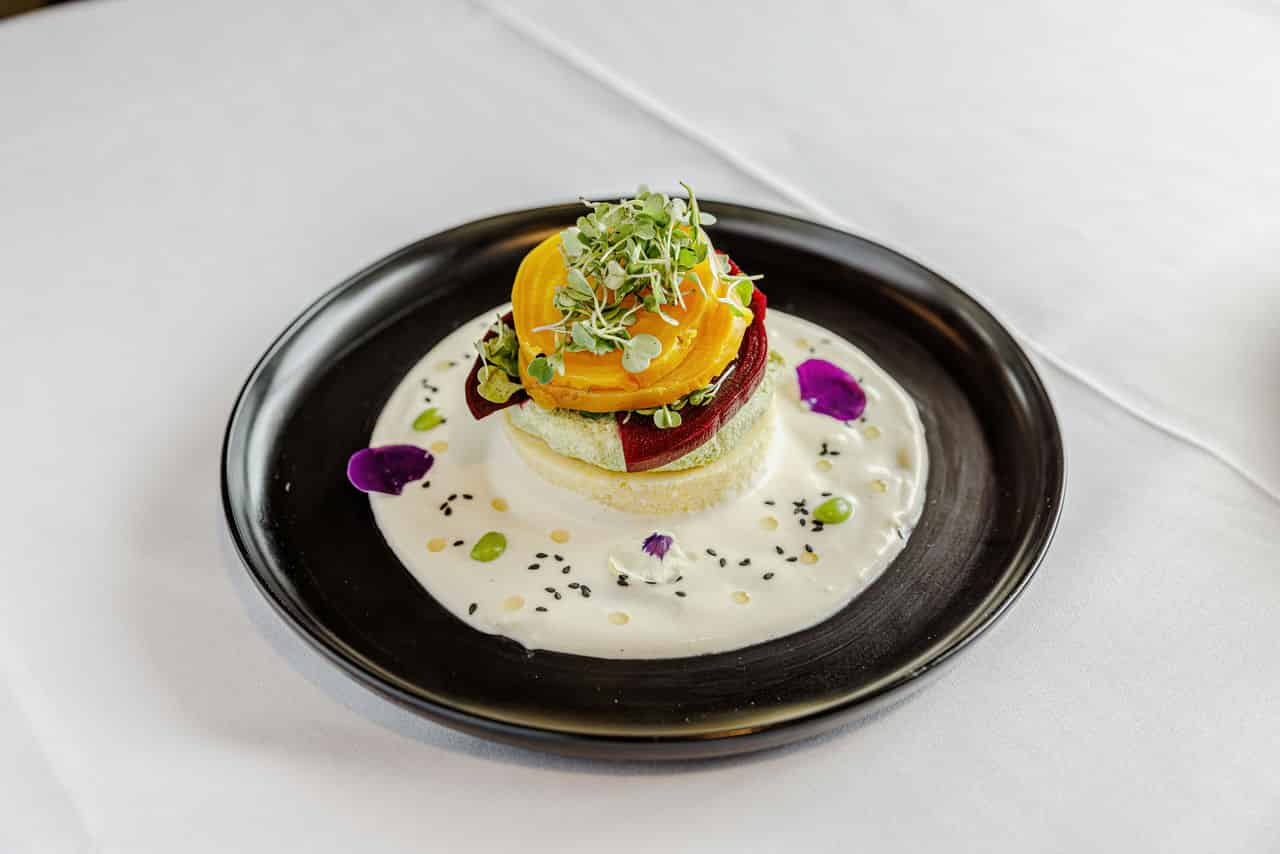 a photo of an elegant dining dish from Mercy Retirement and Care Center's kitchen, garnished with microgreens,sesame seeds and petals