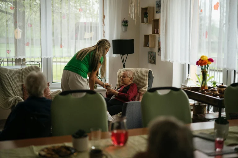 Caregiver assisting elderly resident indoors.