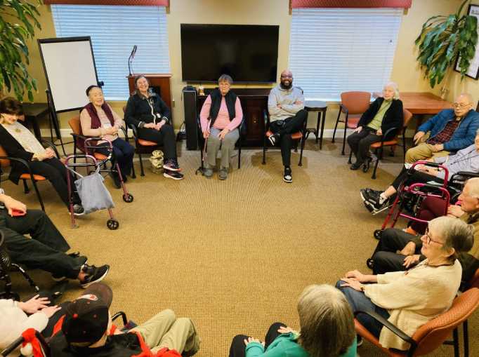 Cleitus Jones joins a group of people sitting in a circle at AlmaVia of San Francisco including several individuals using mobility aids