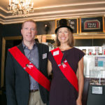 couple poses with red sashes at movie moments event