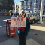 senior care professional holds movie moments sign