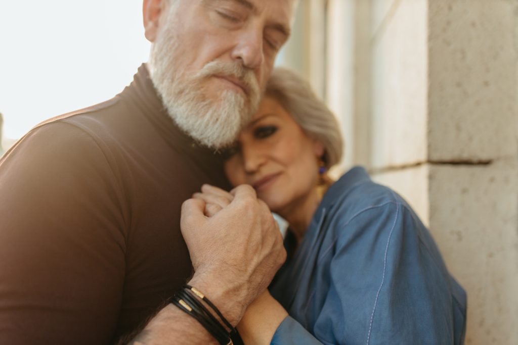 Older man and woman hold hands and hug